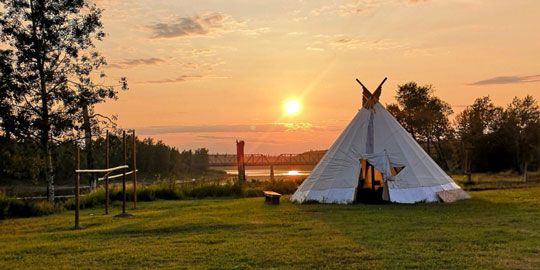 A traditional Cree teepee at sunset, representing land-based education and cultural values