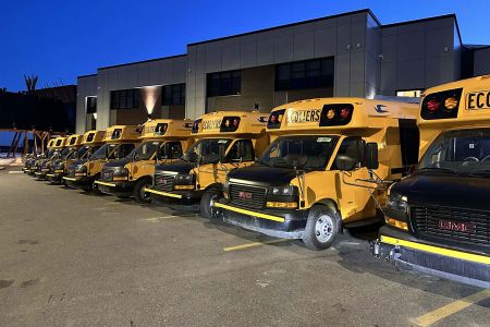 A row of yellow school buses parked in a lot.